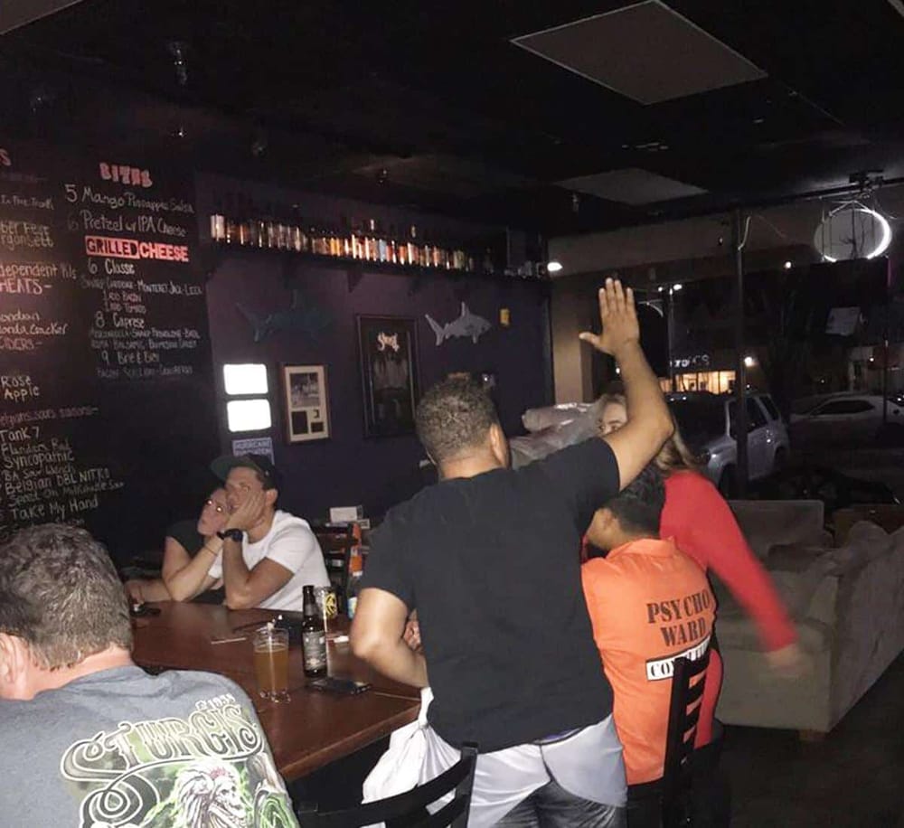 High-energy social scene at a sports bar with patrons enjoying drinks and lively interactions.