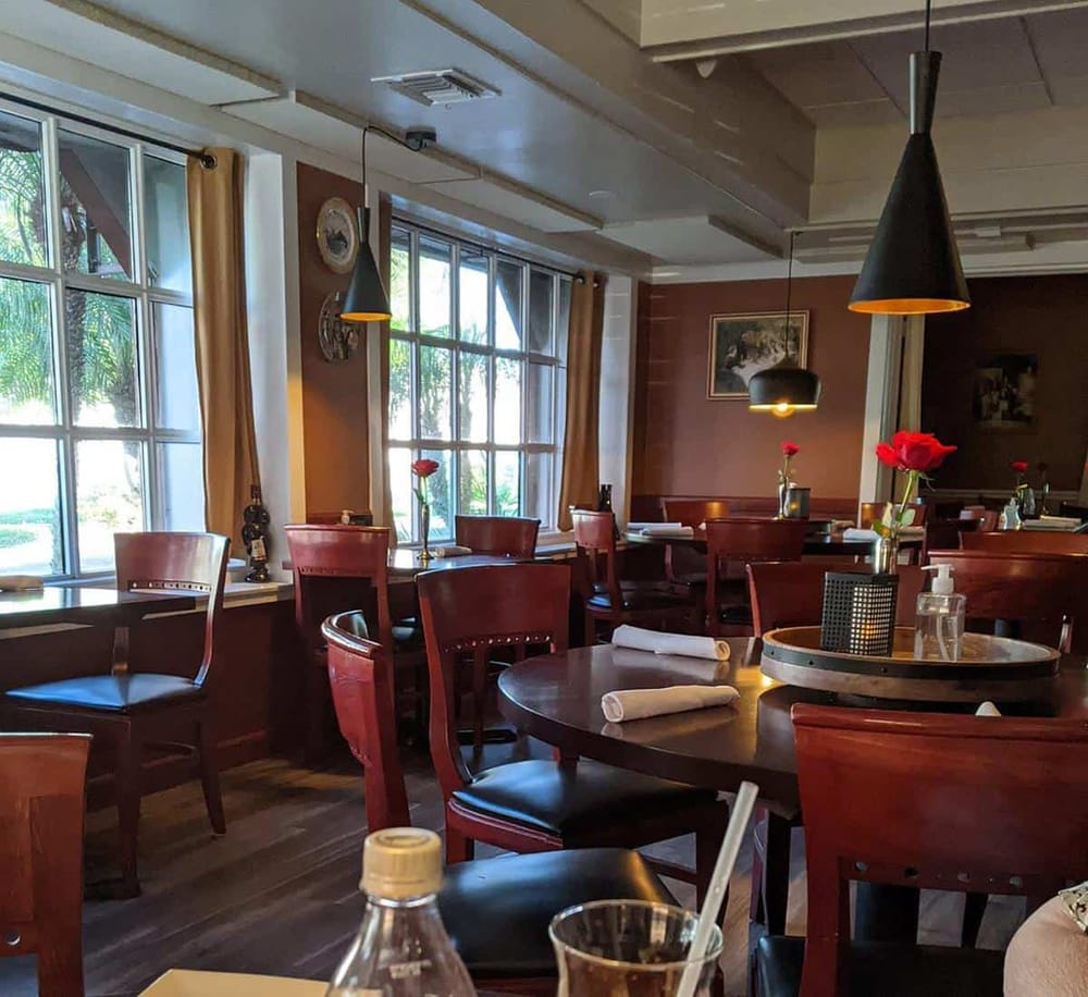 Cozy restaurant interior with wooden dining tables and large windows for natural light.