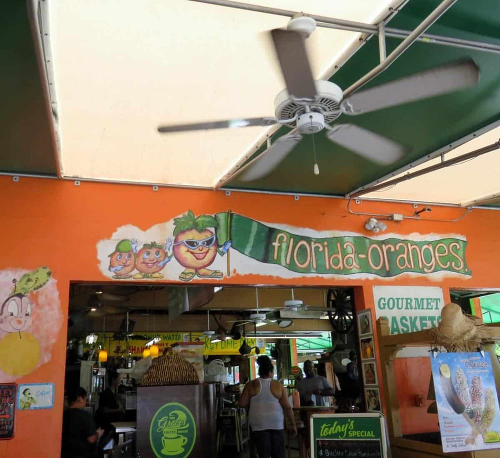 Bright orange storefront for Florida Oranges with cheerful cartoon fruit characters, inviting customers to enjoy fresh citrus treats.