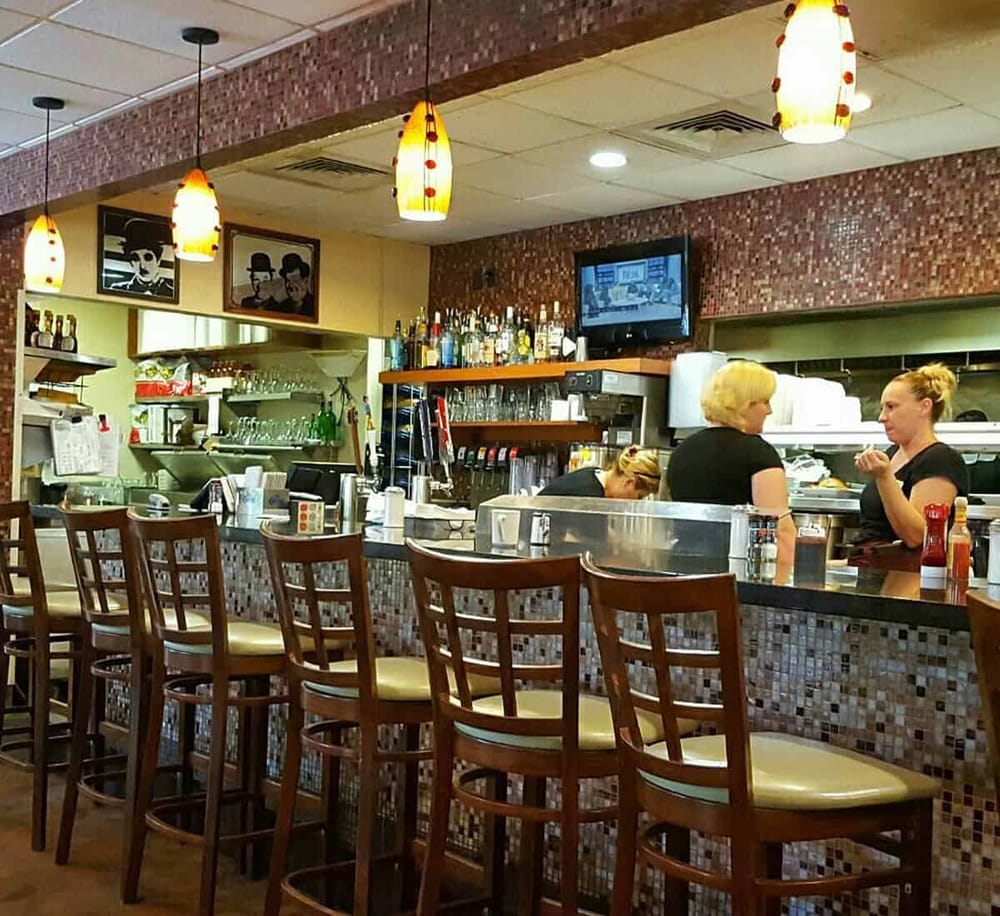 Cozy restaurant interior with bar counter, wooden chairs, and lively atmosphere for dining and socializing.