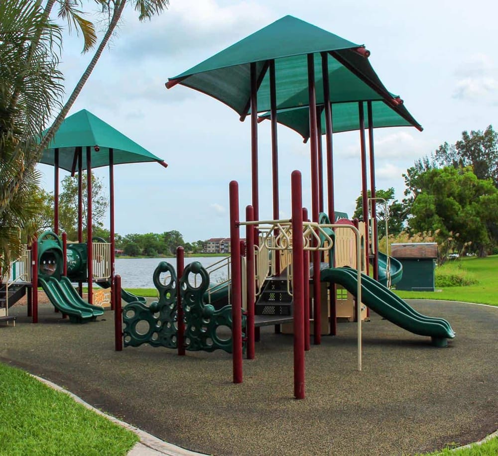 Colorful playground equipment with slides and swings near water, ideal for family recreation and outdoor fun.