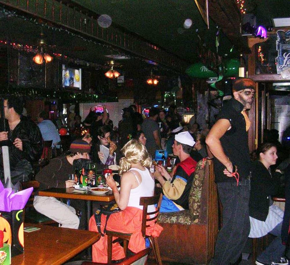 A lively bar scene featuring diverse guests enjoying drinks and entertainment in a cozy, themed nightlife venue.
