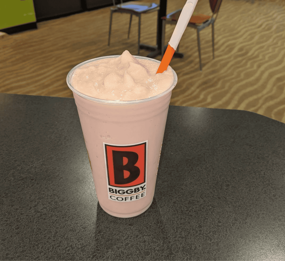 Creamy strawberry smoothie with Biggby Coffee logo on cup, on a black table at the coffee shop.
