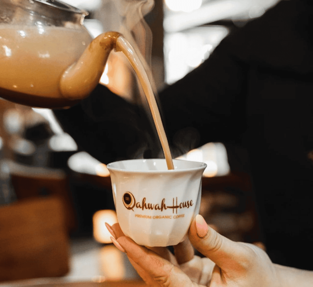 Steaming organic coffee being poured into a ceramic cup at QuestForDirections coffee shop.