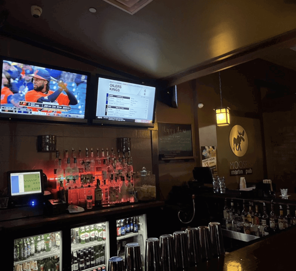 Sports bar with multiple TVs showing sports games, drinks, and a cozy atmosphere.