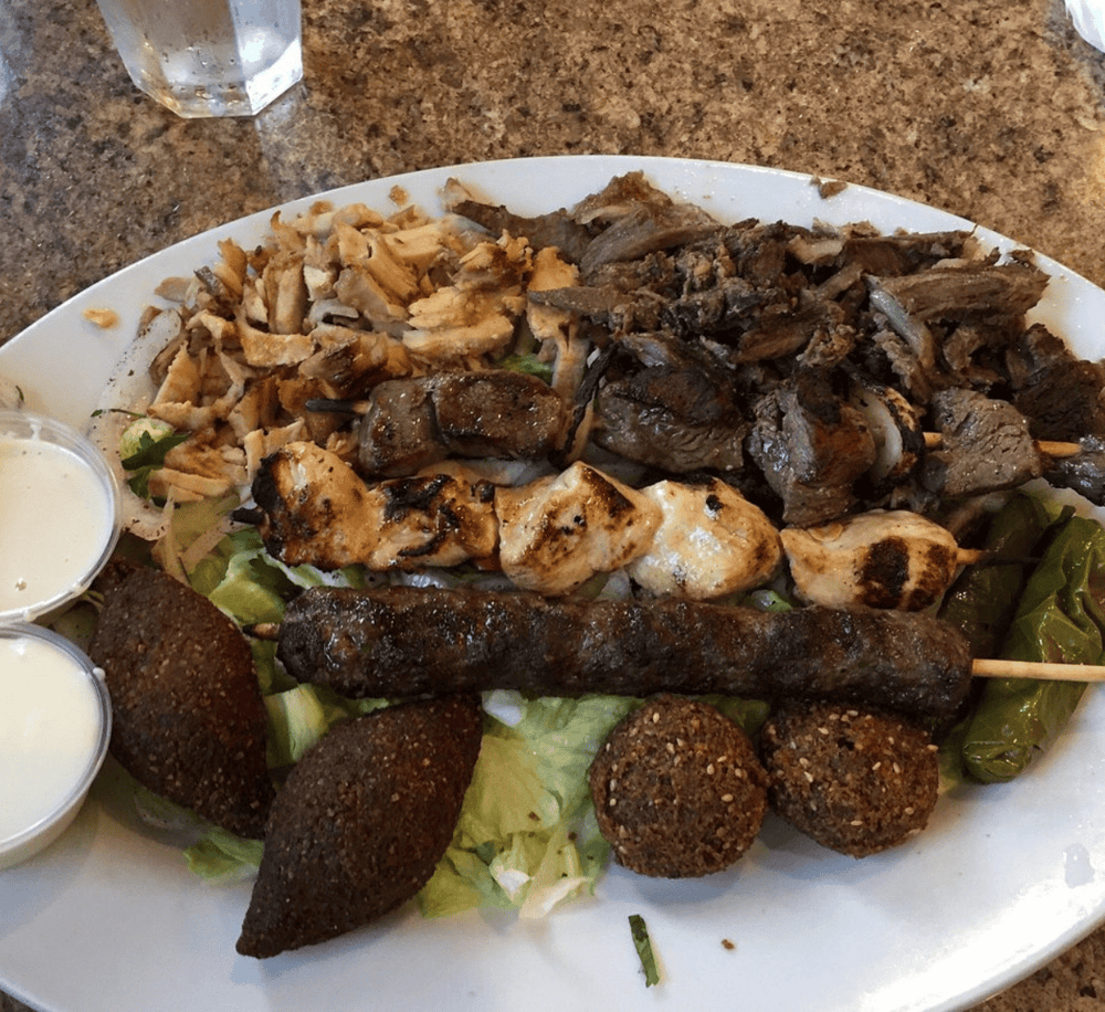 Authentic Middle Eastern mixed grill platter with shawarma, kebabs, falafel, and sauces.