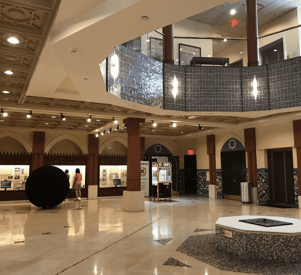 Modern indoor shopping mall interior with cultural design elements and directional signage.