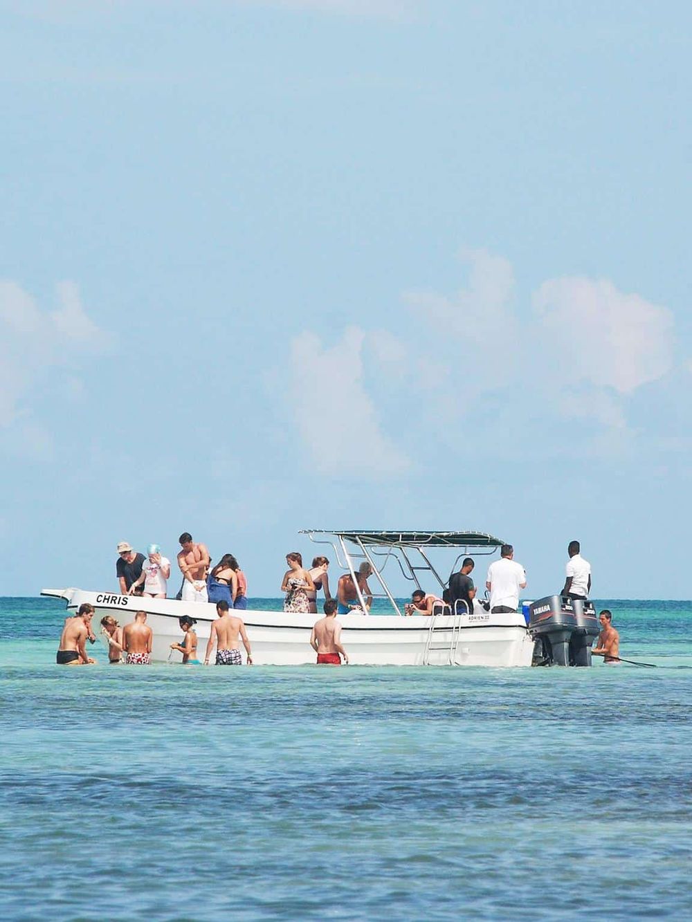 People enjoying boat ride on clear ocean water with blue sky background.