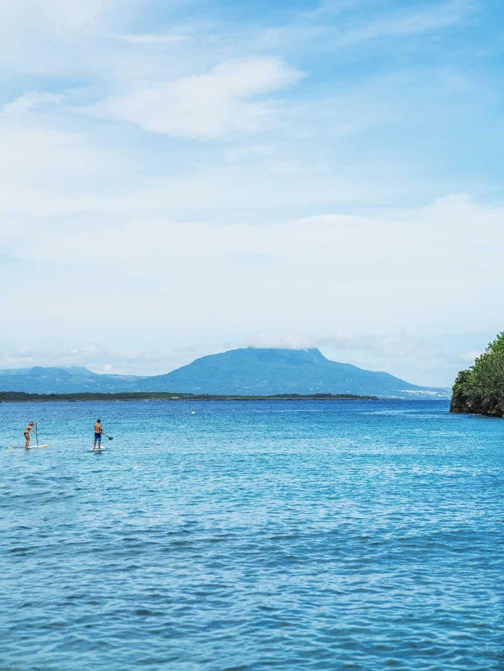 Relaxing water sports at scenic island with mountain views and blue sky.