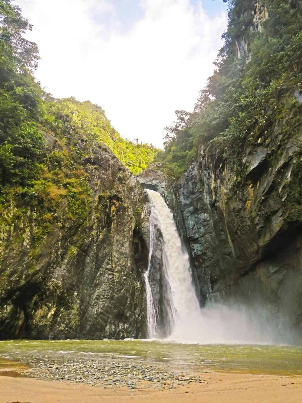 Vibrant waterfall surrounded by lush greenery in a scenic canyon - perfect for outdoor adventures.