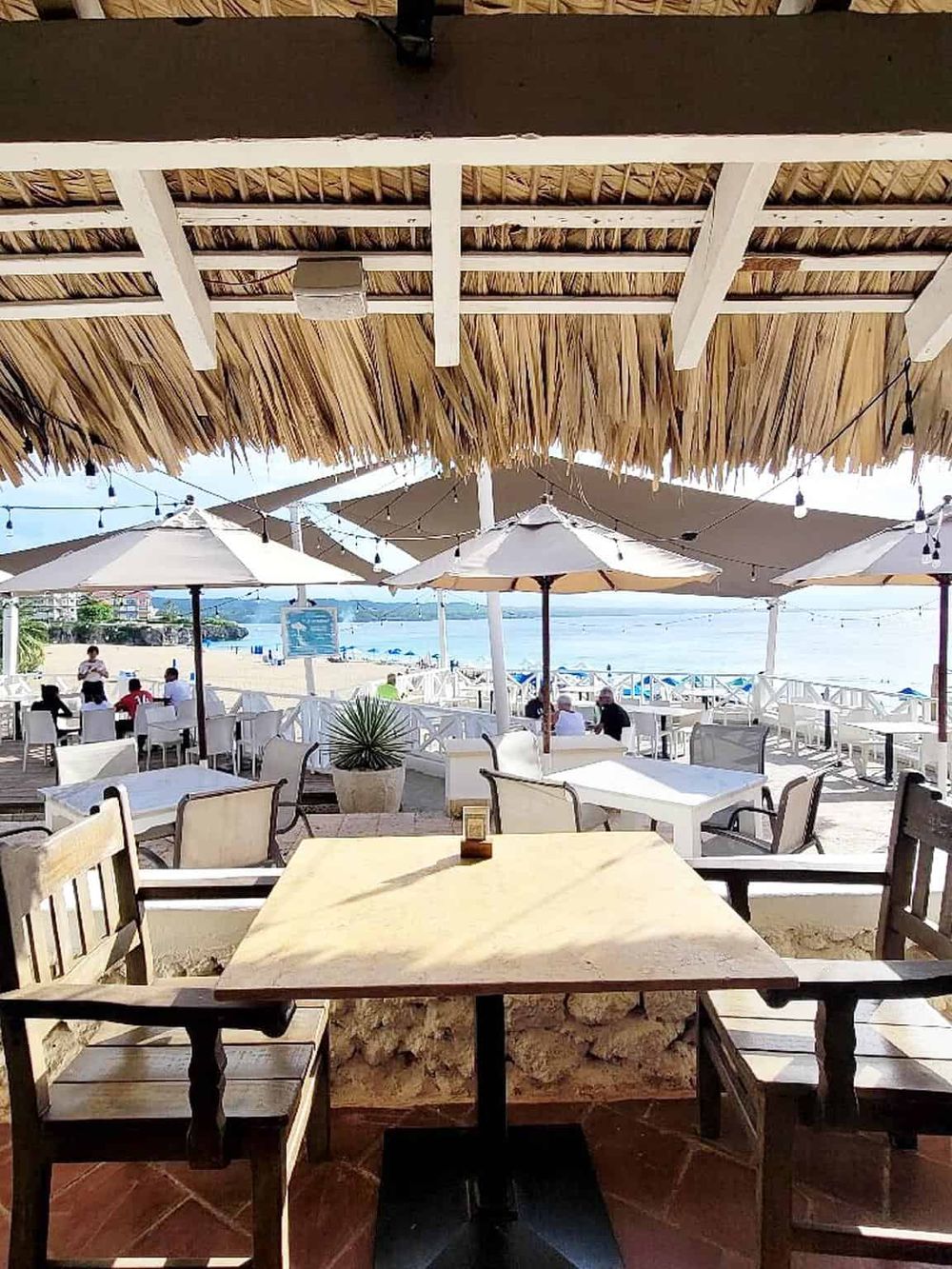 Relaxing beachside restaurant with outdoor seating, umbrellas, and ocean views at Quest For Directions.