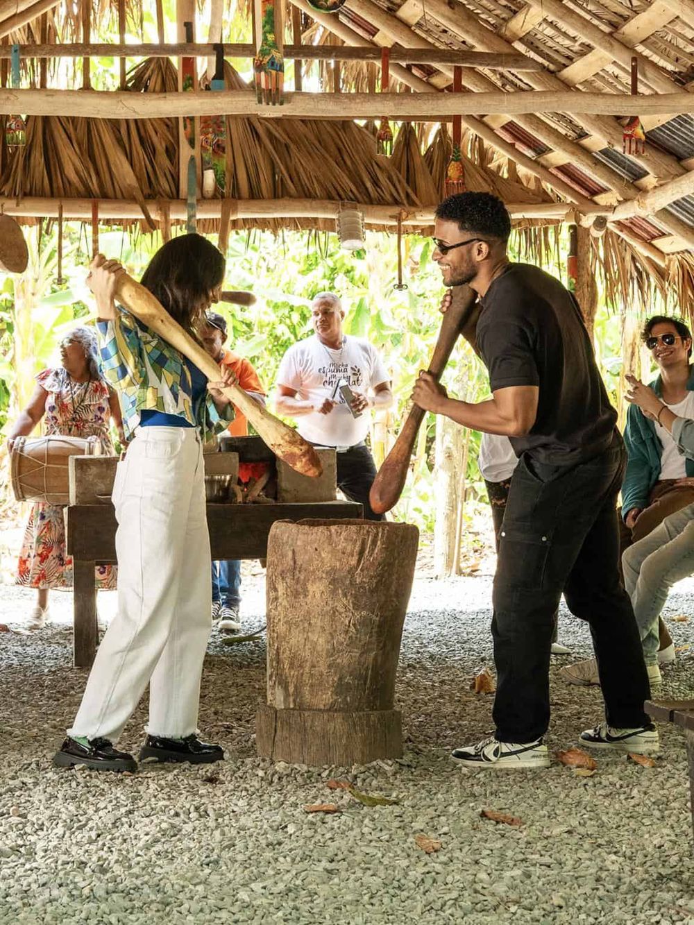 Traditional axe throwing activity in a tribal hut for cultural experience, surrounded by smiling participants.