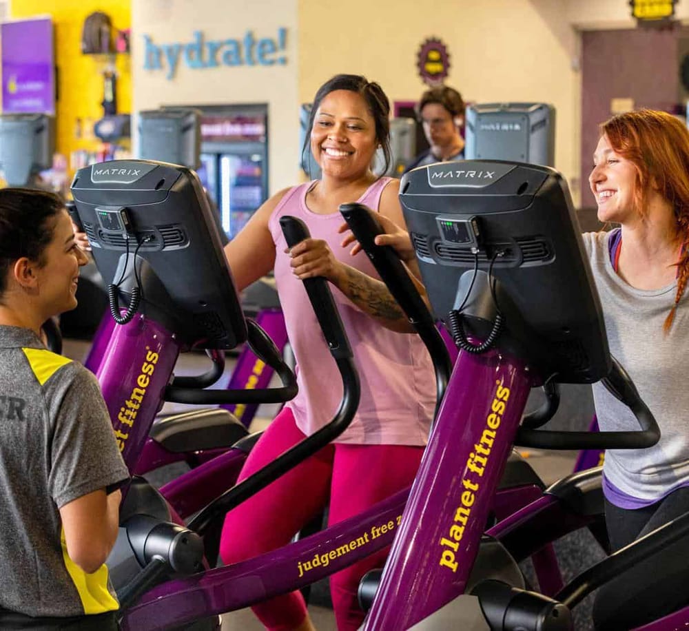 Energetic women using gym treadmill machines at Planet Fitness fitness center.