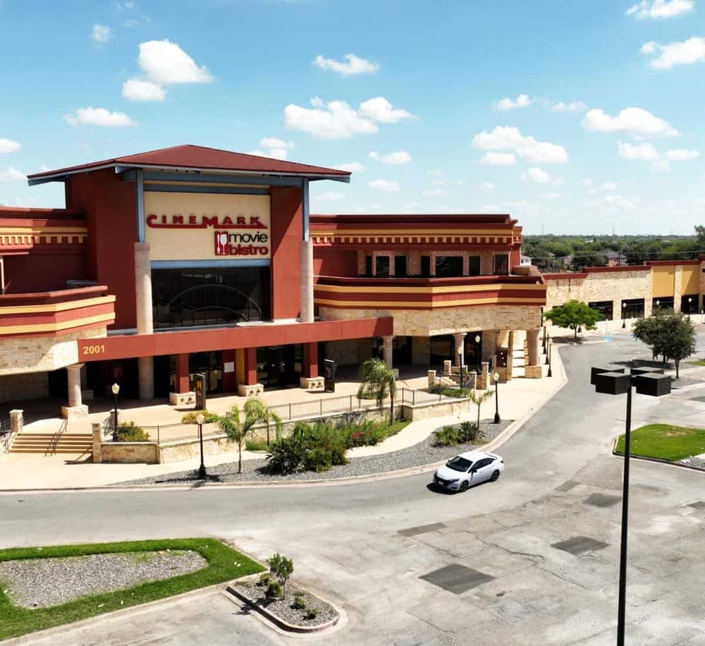 Modern shopping mall with a Cinemark theater and Movie Bistro dining, outdoor parking lot, and landscaped surroundings.