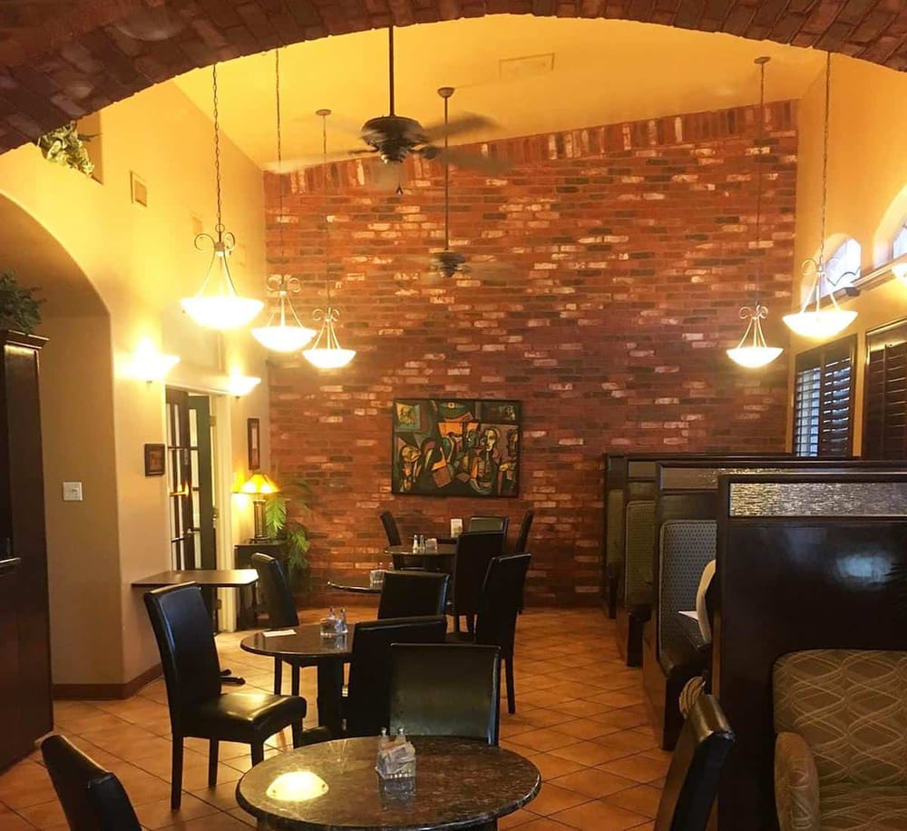 Cozy restaurant interior with brick wall, hanging lights, and seating area for dining.