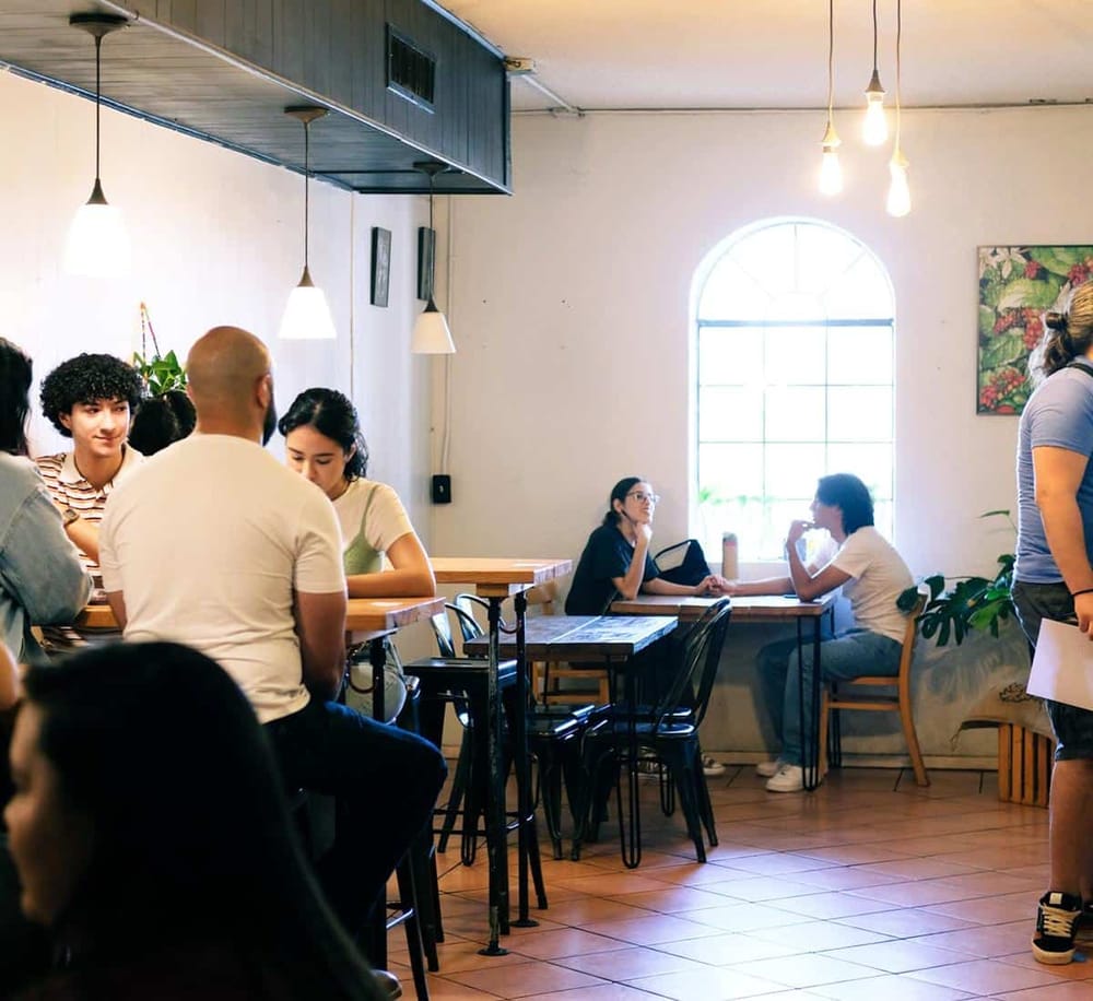 Quiet coffee shop interior with diverse customers enjoying their time and conversations.