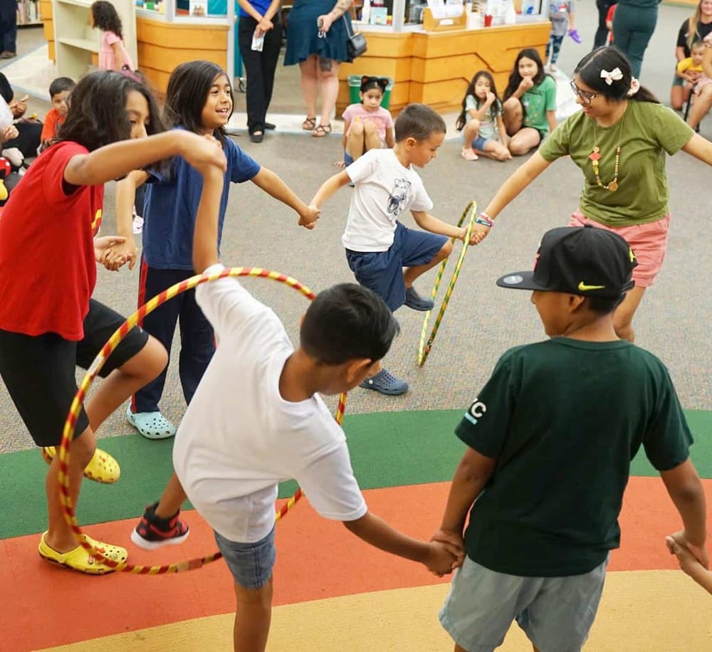 Children playing with hula hoops at QuestForDirections indoor activity center. Fun and engaging kids' entertainment in a vibrant environment.