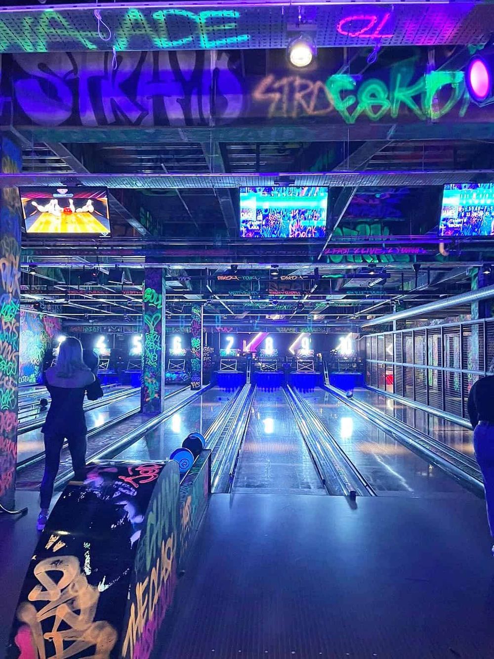 Colorful neon-lit bowling alley with multiple lanes and digital screens, perfect for entertainment and group fun.