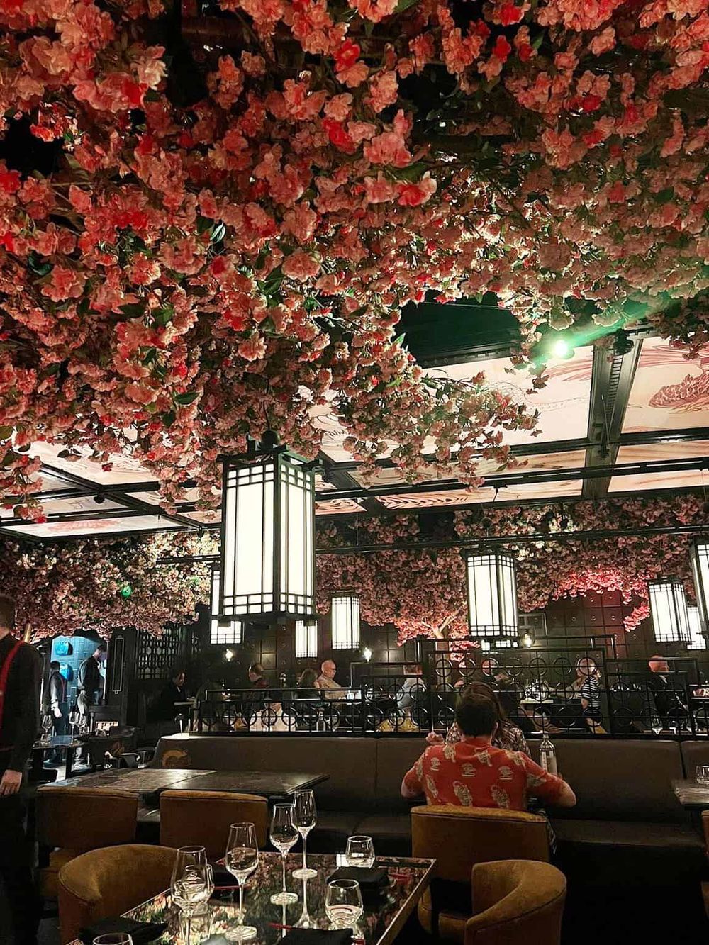 Cherry blossom ceiling decor at upscale restaurant, elegant interior with modern lighting and dining atmosphere.