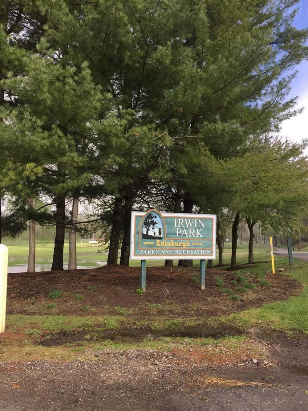Beautiful park entrance sign at Irwin Park in Edinburgh, surrounded by lush trees and vibrant greenery.