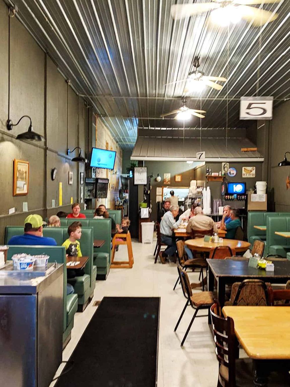 Cozy restaurant interior with diners, ceiling fans, and vibrant atmosphere for dining out.