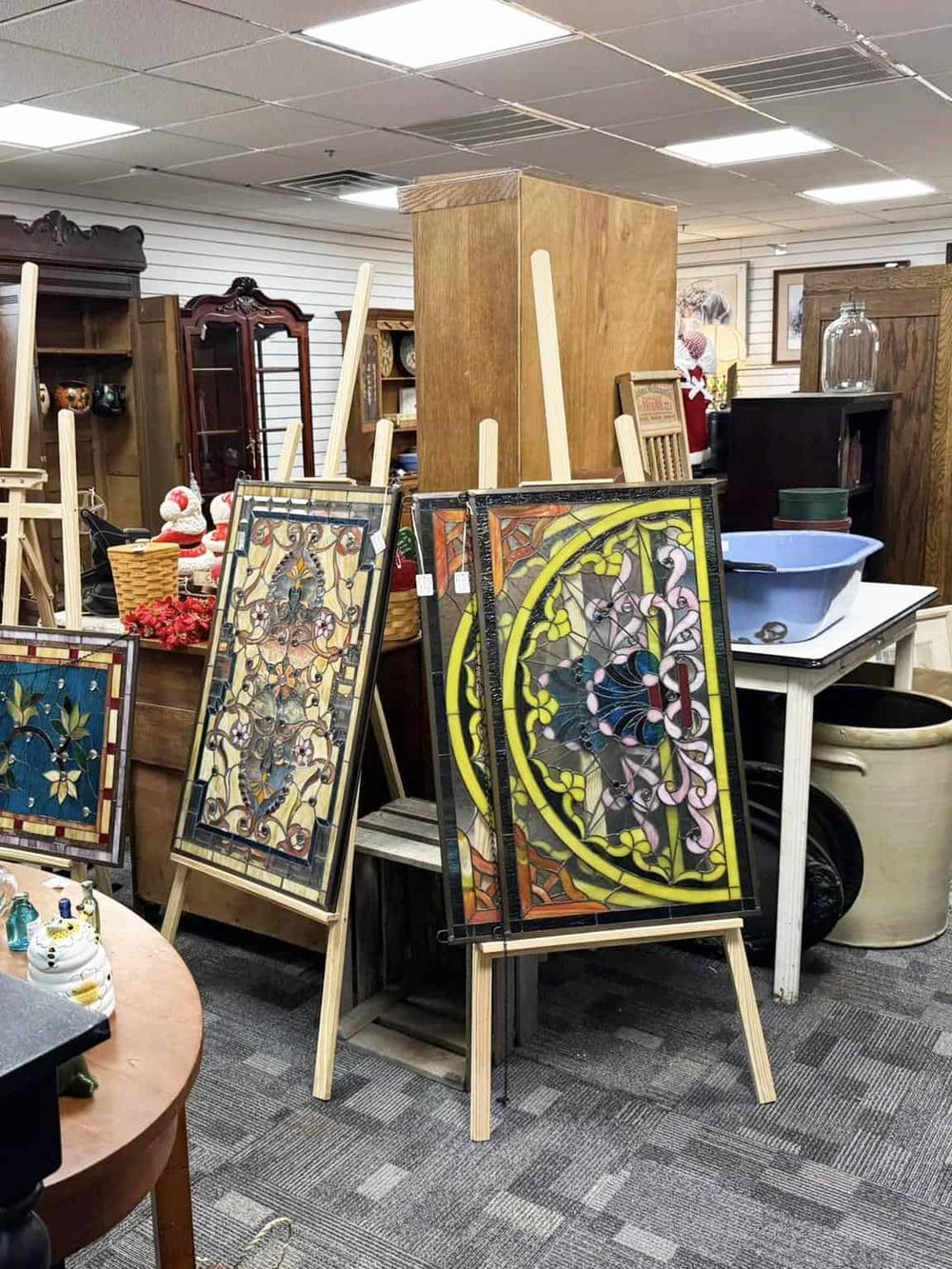 Colorful stained glass artworks on display at an antique shop or thrift store.