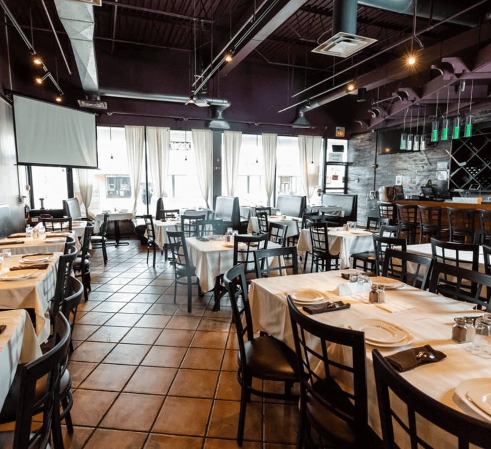 Cozy modern restaurant interior with white tablecloths and natural light for dining ambiance.