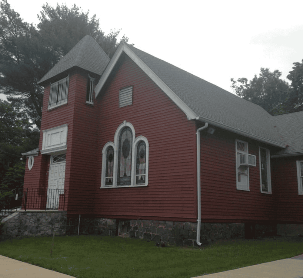 Victorian-style house with red siding, arched windows, and a steep roof, showcasing classic architecture.