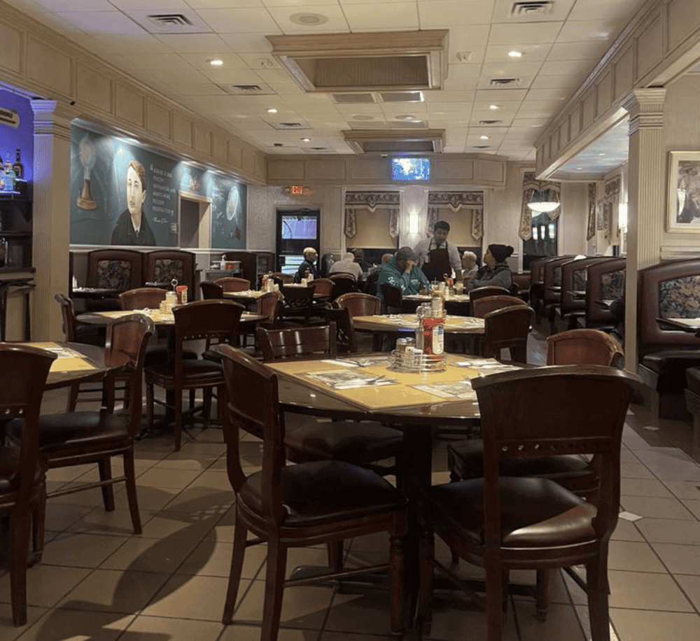 Cozy restaurant interior with wooden seating, murals, and diners enjoying meals, perfect for dining out and family gatherings.