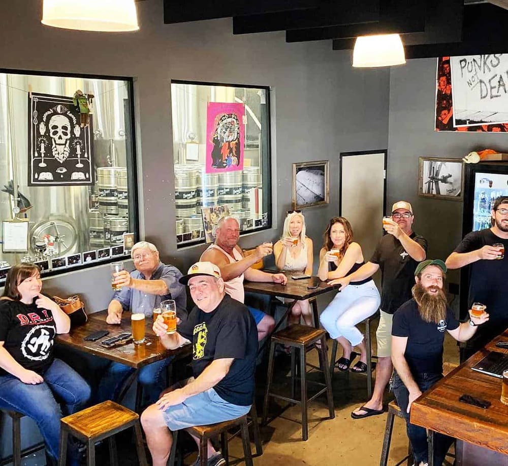 A lively group enjoying craft beers at a brewery with punk rock artwork on the walls.