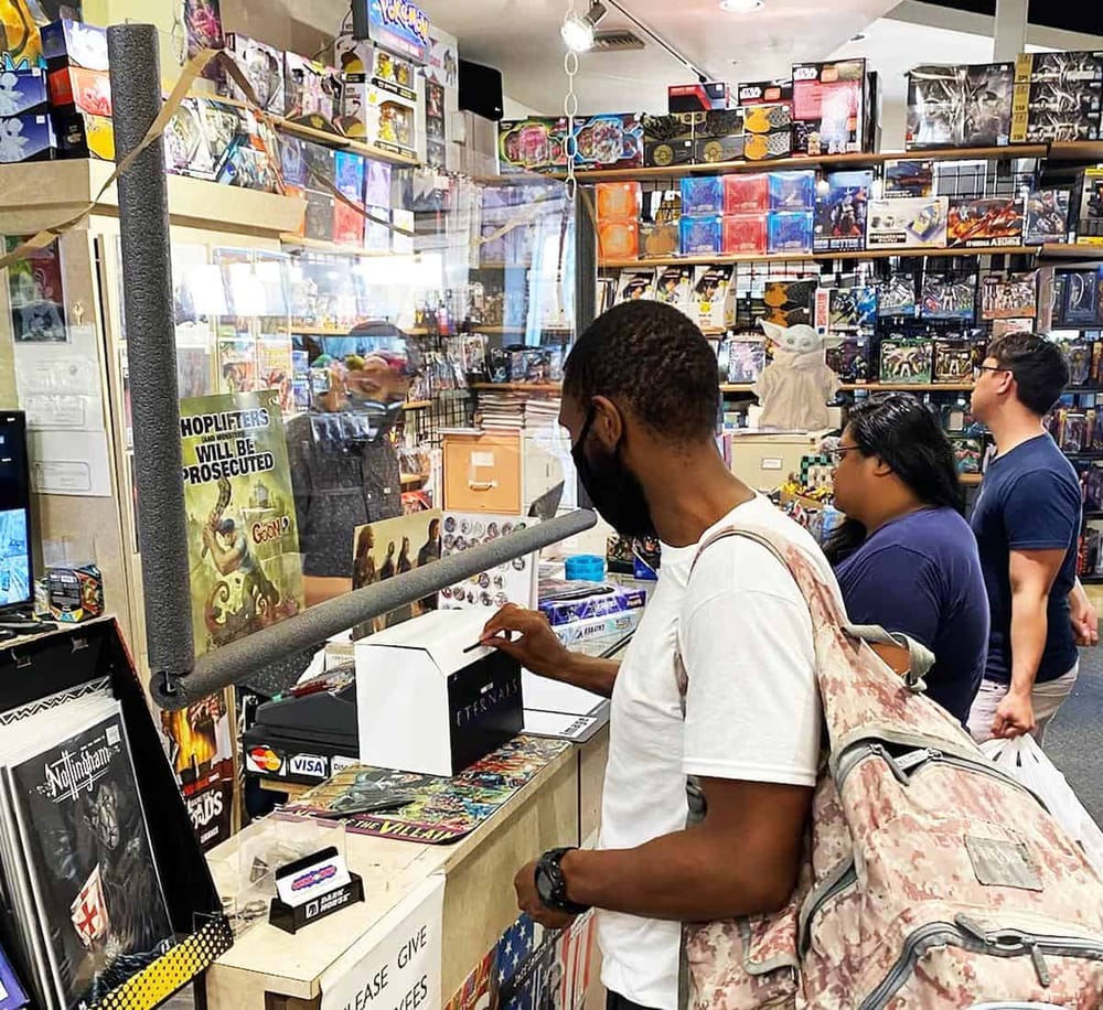 1. People shopping for board games and collectibles at a gaming store checkout counter.