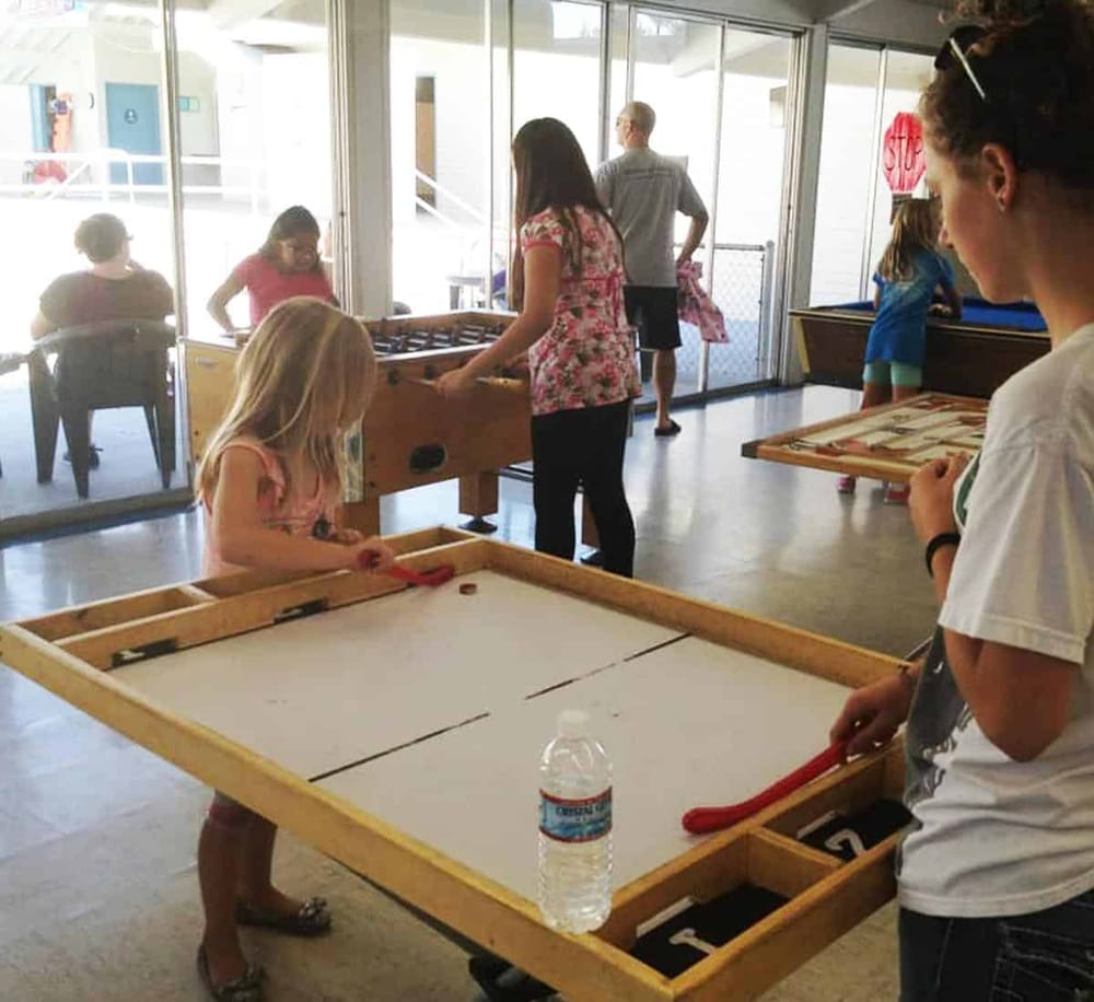 Children playing air hockey in an indoor arcade area.