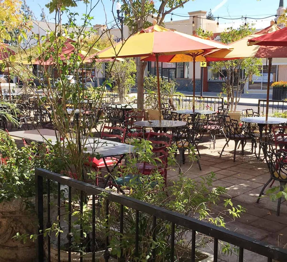 Cozy outdoor café with colorful umbrellas and lush greenery, perfect for relaxing dining and socializing.