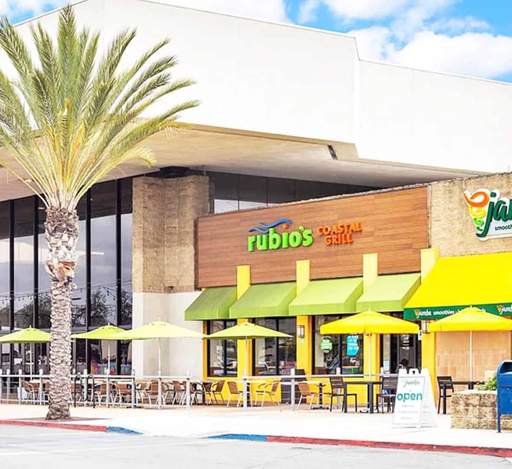 Bright storefront of Rubio's Coastal Grill with outdoor seating and colorful umbrellas.