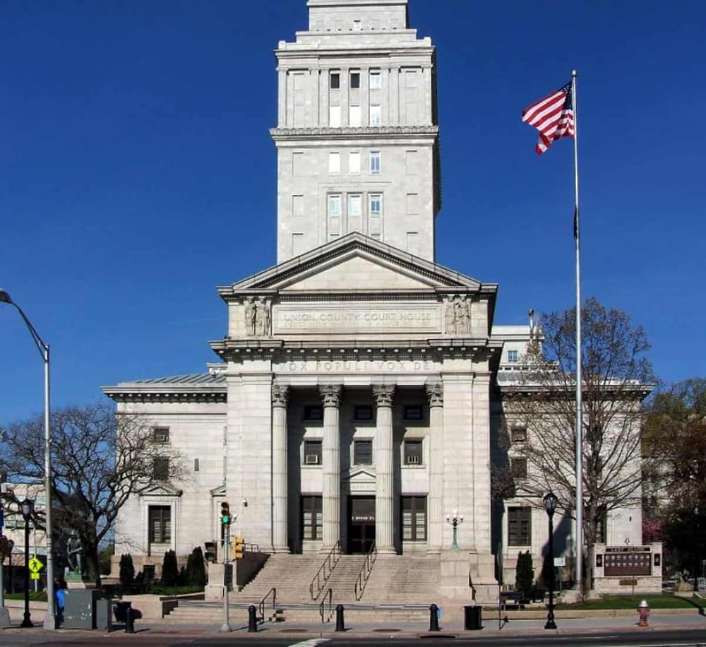 Historic courthouse building with American flag in a city setting, representing local government and legal services.
