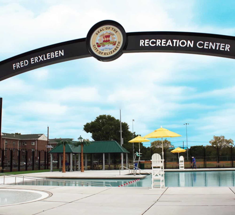 Spacious outdoor swimming pool at Fred Erxleben Recreation Center, surrounded by shaded seating and recreational facilities.