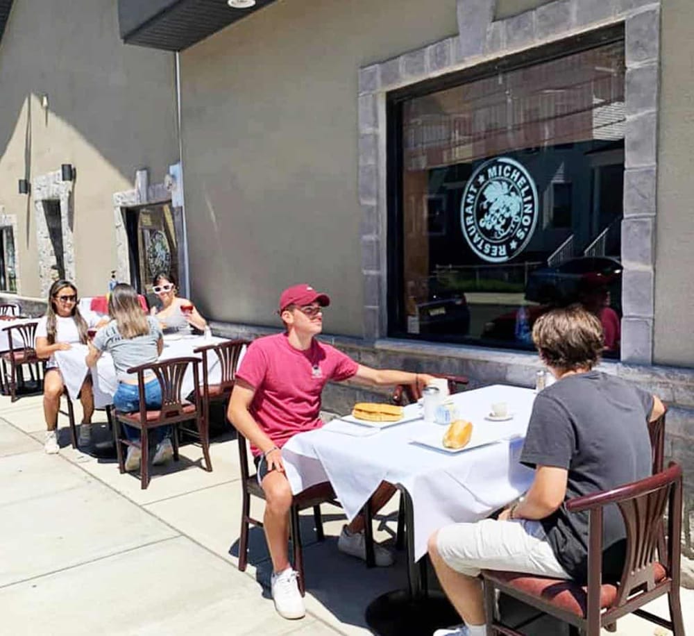 Outdoor dining at a restaurant with people enjoying meals on a sunny day.