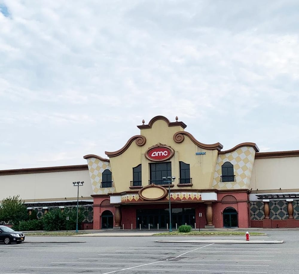 Amc theater building exterior at dusk with parking lot in front, part of QuestForDirections image collection.
