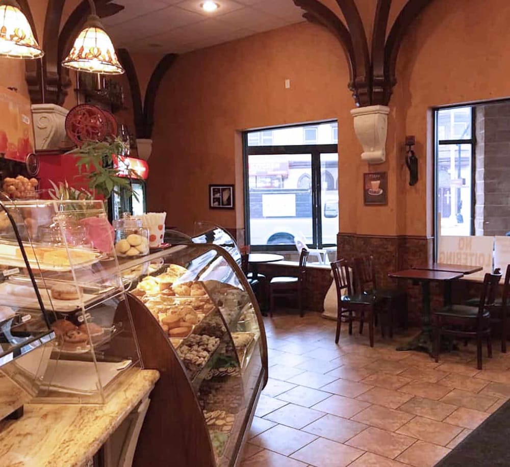 Warm European-style bakery interior with pastry display case and cozy seating area.