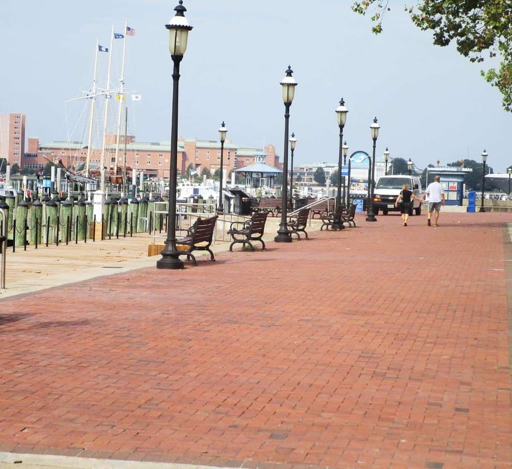 Colorful waterfront promenade with benches, lampposts, and boat docks at a marina.