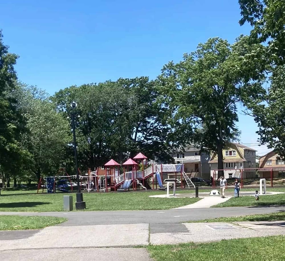 Colorful children’s playground at a neighborhood park with slides, swings, and climbing structures under a bright blue sky.