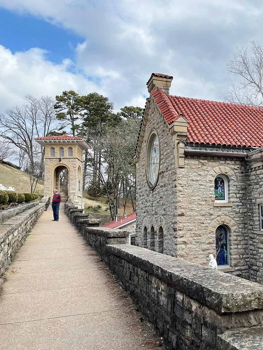 Chapel with red tile roof and stone walls, scenic walkway with person, iconic architecture at Quest for Directions.