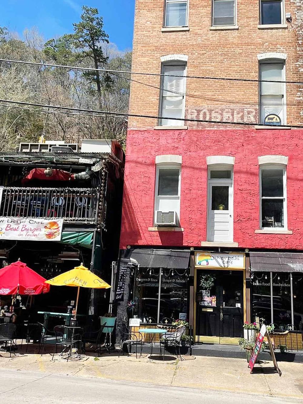 Charming sidewalk cafe exterior with outdoor seating and vibrant umbrellas in front of a brick building.