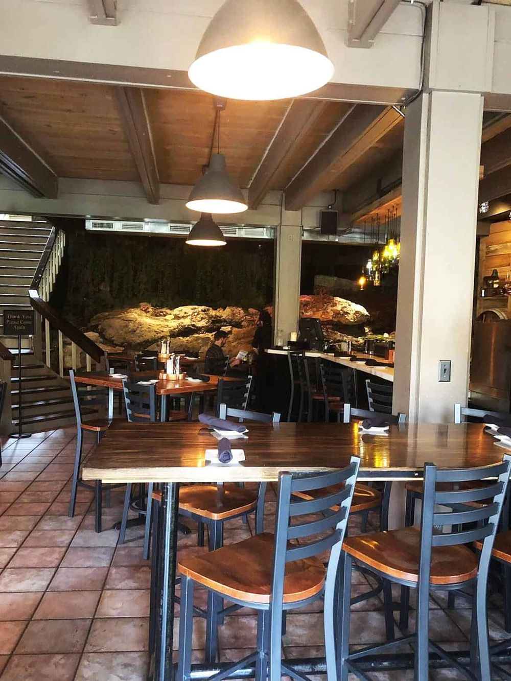 Cozy restaurant interior with wooden accents, modern lighting, and a rock feature wall for a unique dining experience.