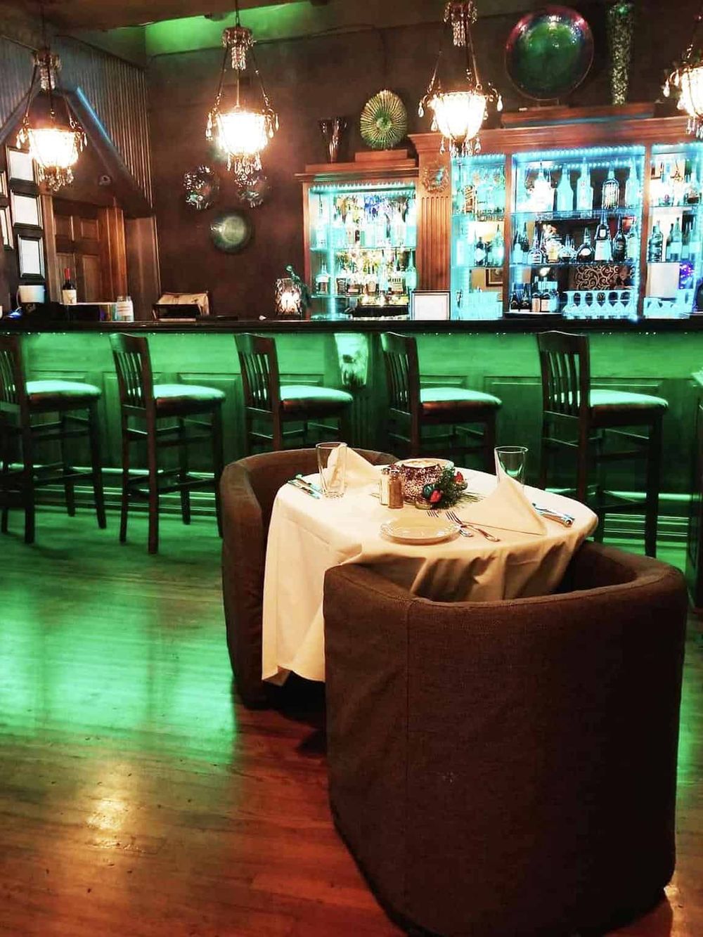 Elegant bar and dining area with cozy table setting and vibrant lighting ambiance.