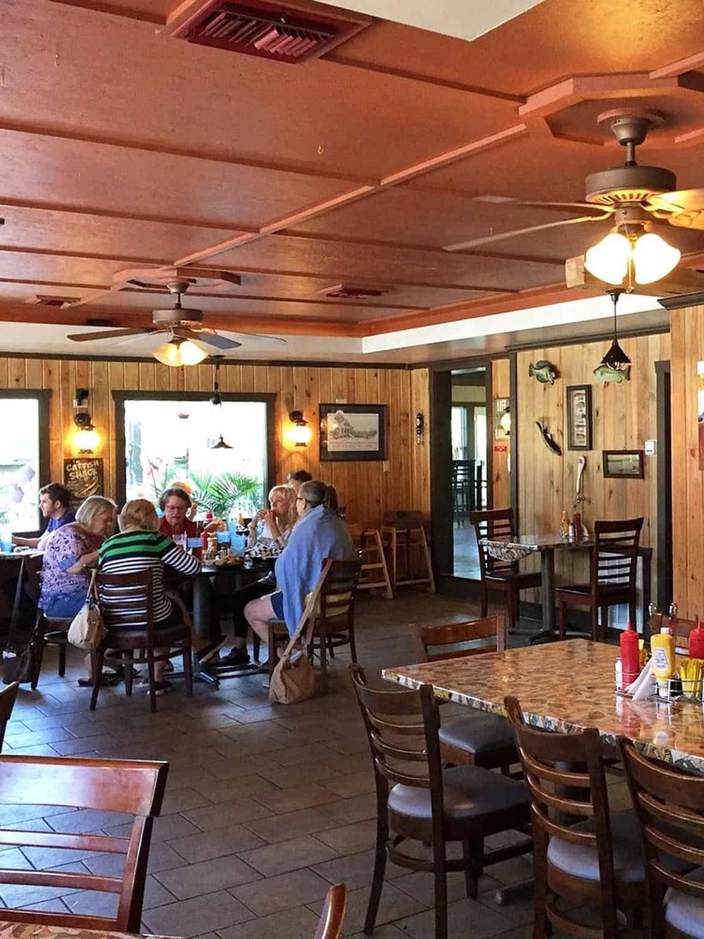 Cozy restaurant interior with wooden walls and ceiling fans, perfect for casual dining and group gatherings.
