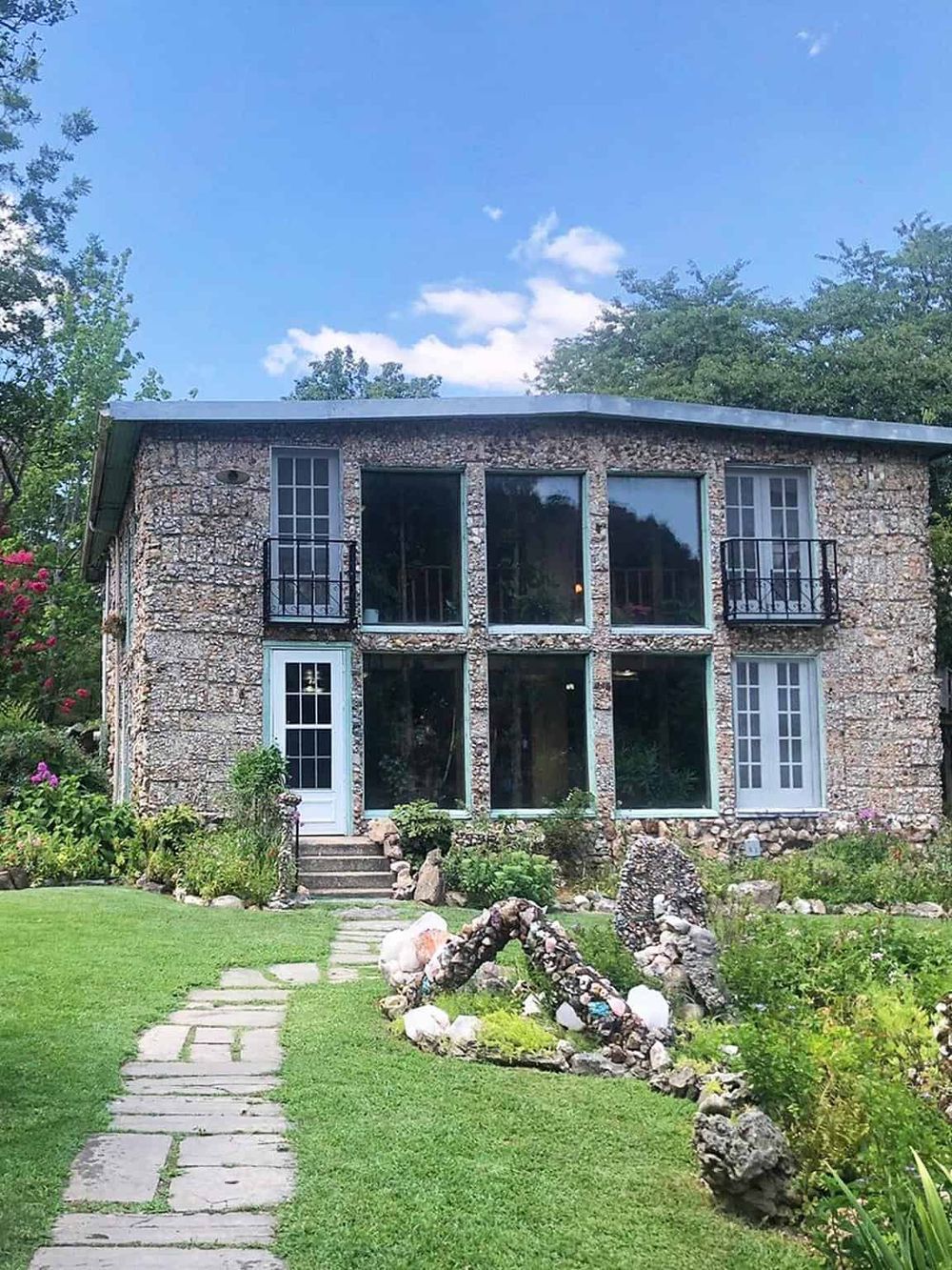 Stone house with large windows and garden, modern architecture, lush green landscape, perfect for scenic retreats.