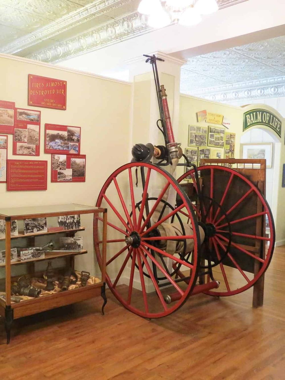 Antique fire hose cart display at Quest for Directions museum, showcasing firefighting history.