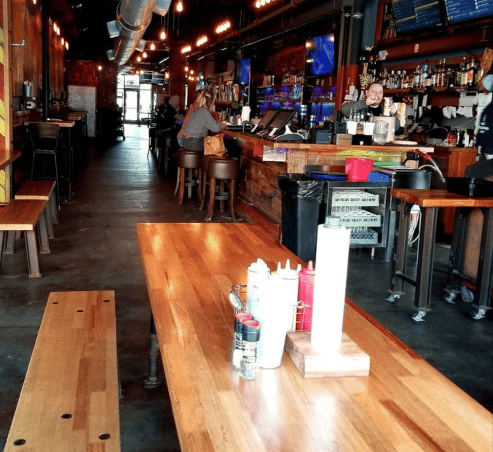 Relaxed bar with wooden decor, order drinks at the counter, casual dining atmosphere, QuestForDirections, urban trendy bar scene.