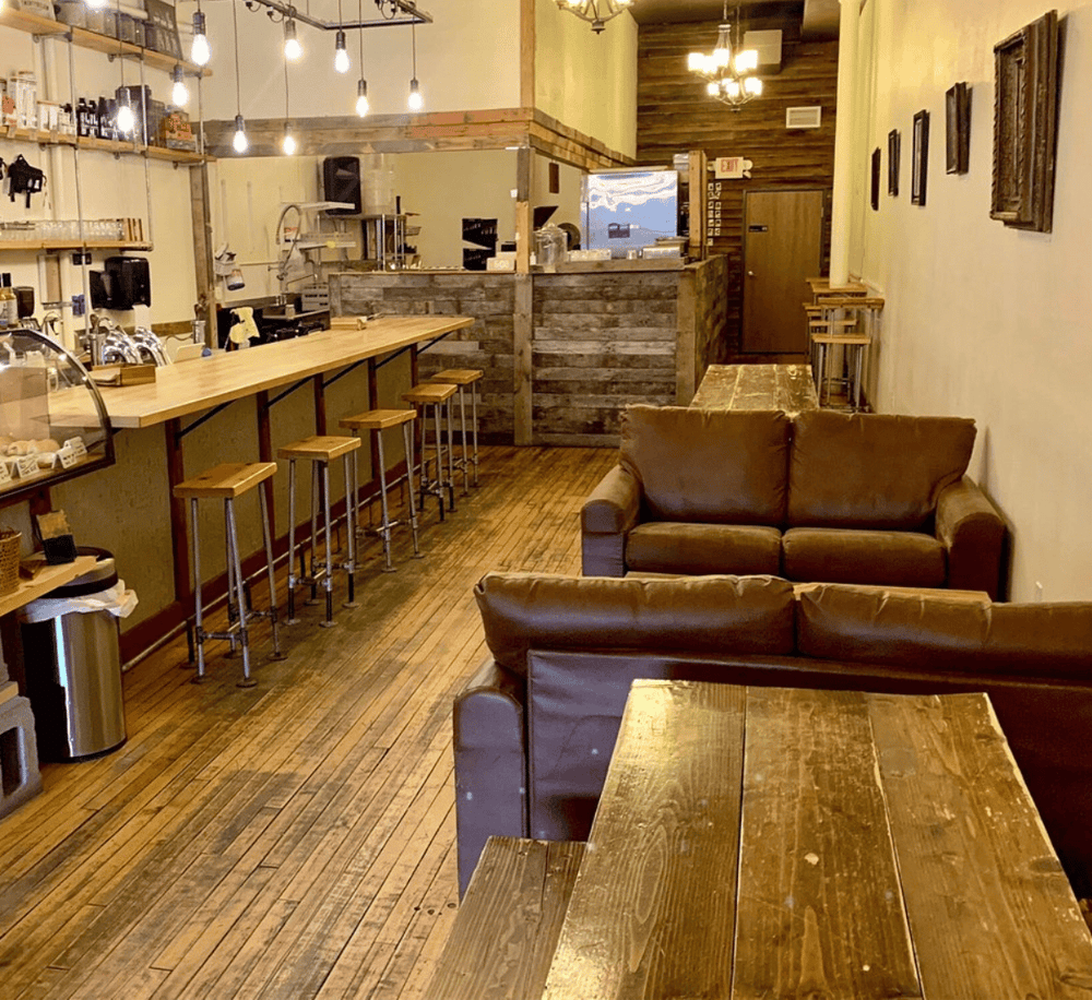Cozy coffee shop interior with rustic wooden decor and comfortable leather seating.
